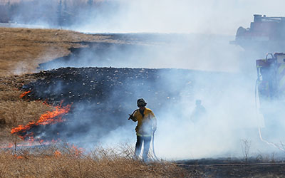 A fire fighter pulls a hose while trying to put out a grass fire east of Cheyennes South High School Sunday afternoon. The blaze charred the grassy area between South and Triumph High School and close College Drive for about on hour. To view more images from the fire check out http://shutterspeed.wyomingnews.com.