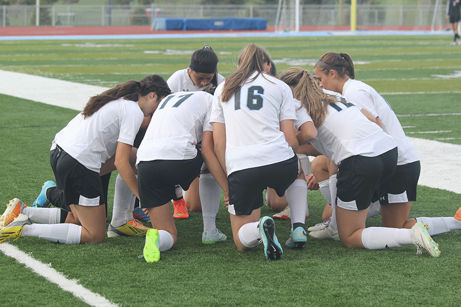 The Lady T-Birds kneel in a huddle before their cross town rivalry game
