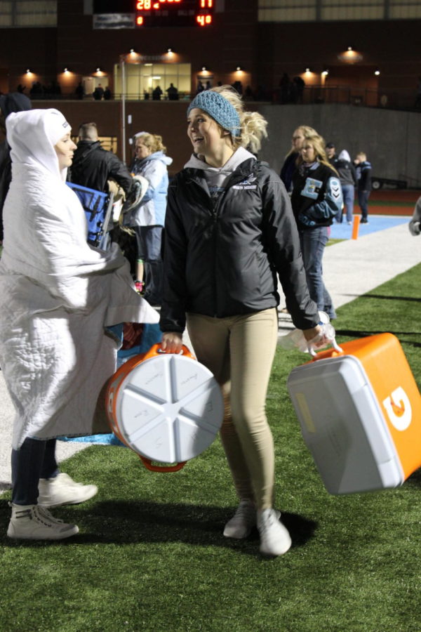 Senior Tatum Hayes carries water jugs after refilling the Football teams bottles after the Homecoming game against Easts rivals, Central. 